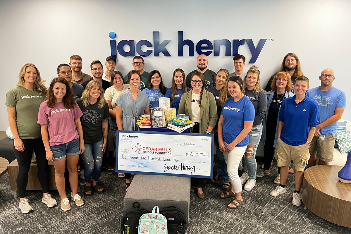 Jack Henry associates posed for a photo alongside donated school supplies and hygiene items