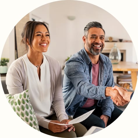 multiethnic couple smiling while shaking hands with consultant at home