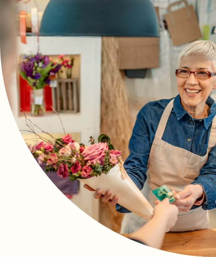 mature, gray hair, flower shop owner receiving a payment from a customer with a credit card