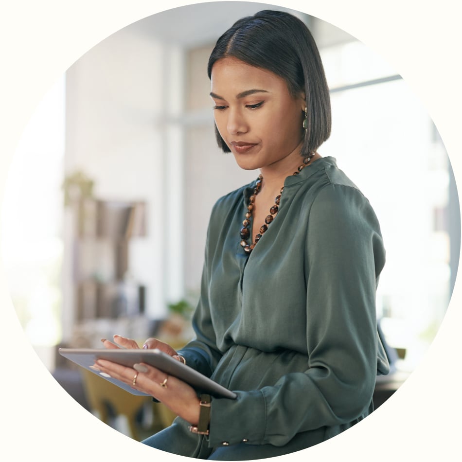 stylishly dressed woman reviews data on tablet in a bright, open concept modern office