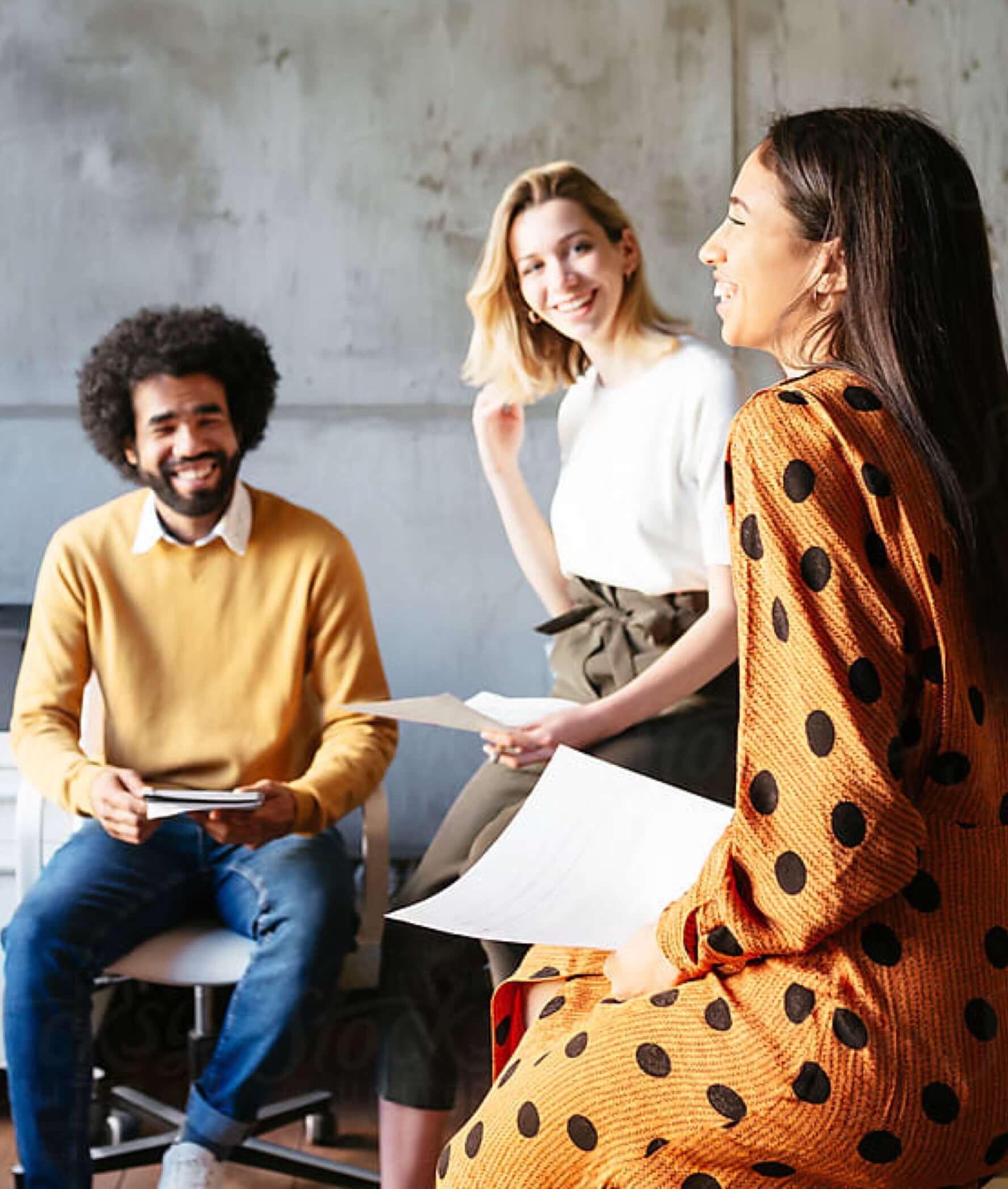 three coworkers smiling holding papers