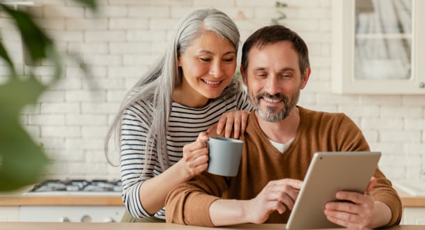 Happy mature middle-aged couple checking bank account on digital tablet
