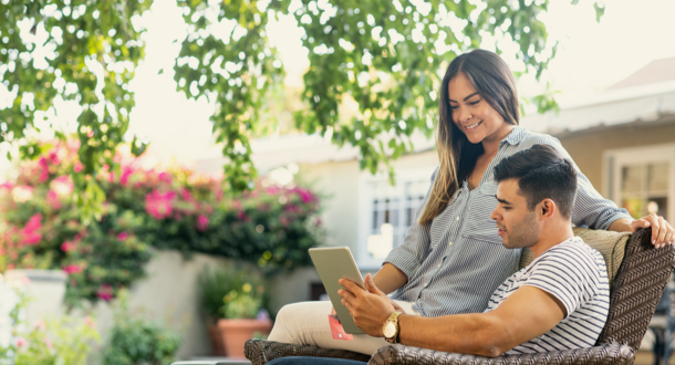 a couple scrolling on an ipad on a bench 