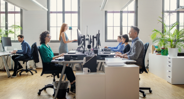 Business people at their desks in a busy, open plan office