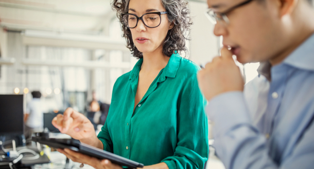 Businesswoman reviewing data analytics on digital tablet with colleague