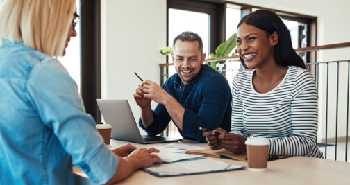 Young African American businesswoman laughing while talking with colleagues during a meeting around a table