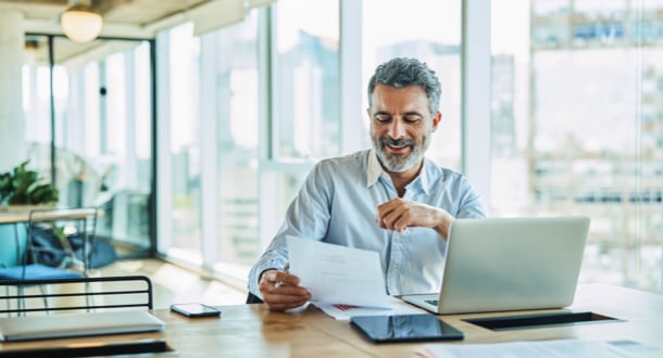 Older businessman smiling while reading document