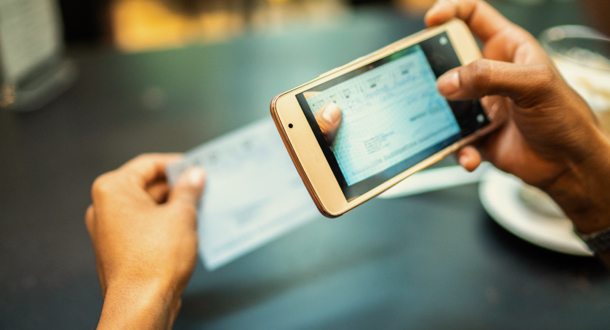 Closeup of woman depositing check by phone