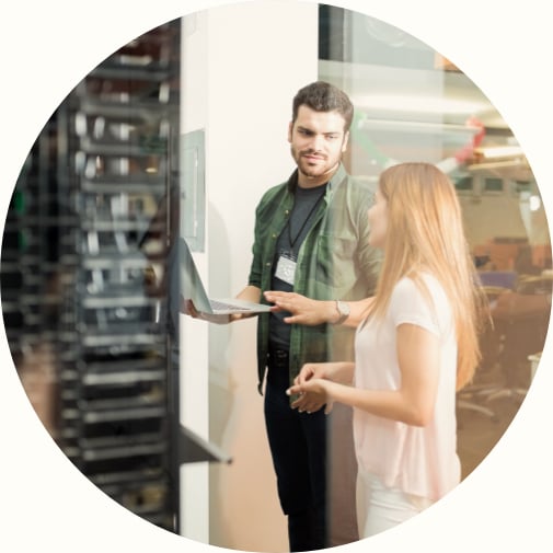 Two business people standing in server room with laptop