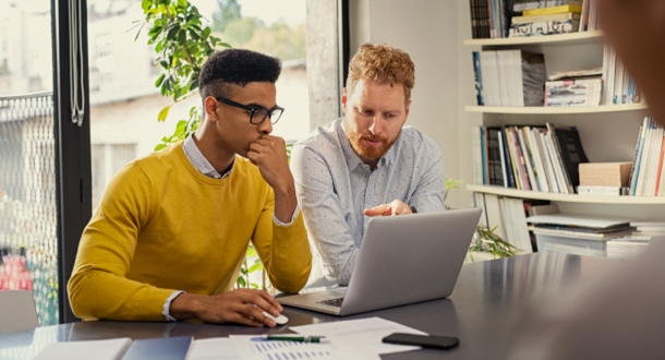 Two businessmen working together on laptop