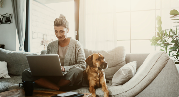 Businesswoman working on laptop computer sitting at home with a dog 