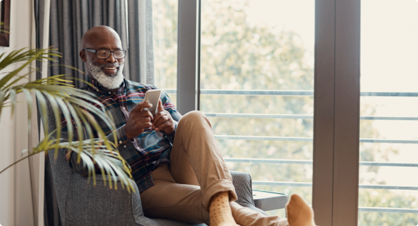 mature man using a cellphone while relaxing on a sofa at home