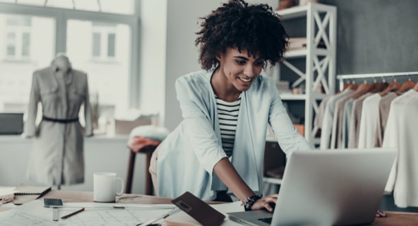 young African woman working using computer and smiling while standing in workshop