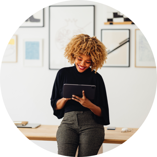 Smiling African-American Woman Standing in an Office and Looking at a Digital Tablet