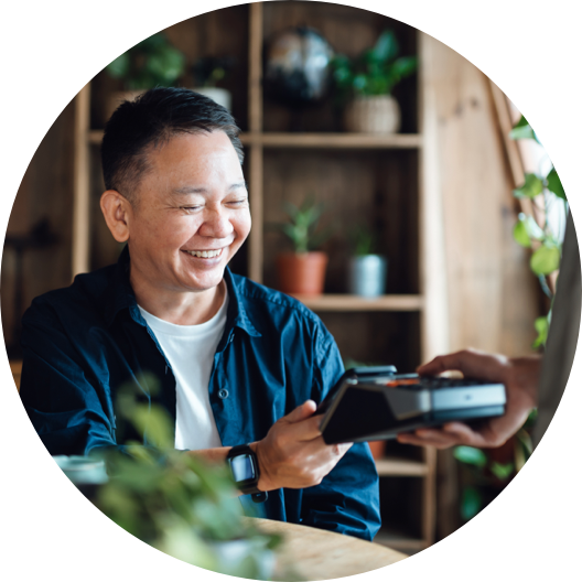 Senior Asian man paying bill with credit card contactless payment on smartphone in a cafe