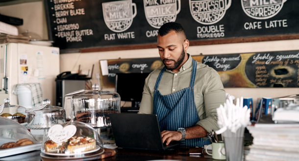 Coffee shop employee working on laptop in cafe
