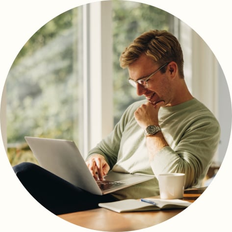 Young man smiling at home using laptop