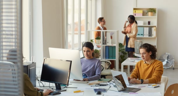 Colleagues using computers while working in the office