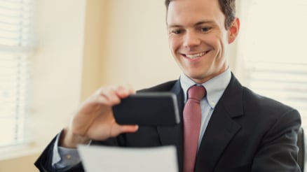 Business man using his smartphone to remote deposit his check