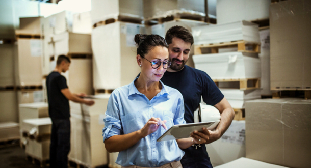 two warehouse employees reviewing information on a tablet