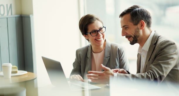 Happy male and female sitting in cafe discussing online financial news