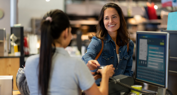 Cheerful female customer making a contactless payment with credit card at a furniture store smiling