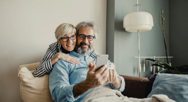 Senior couple is in the living room talking and using smart phone