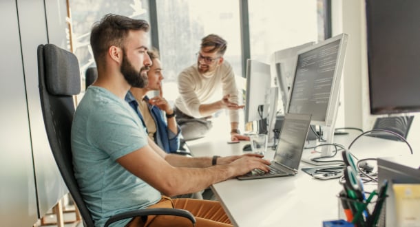 Young male programmer sitting at the desk in his office and working.