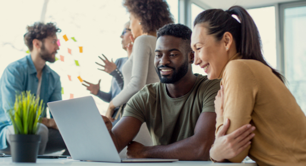 Two coworkers sitting at table collaborating over laptop