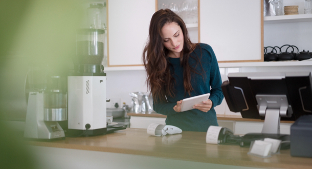 woman in coffee shop reviewing information on tablet device