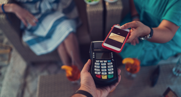 Friends in cafe paying contactless with smartphone