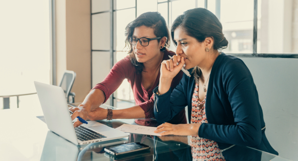 Two women meeting in office collaborating on laptop