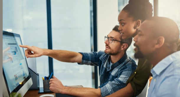 three businesspeople working around a computer in the office