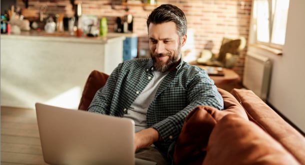 young man using laptop on couch at home