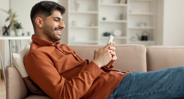 male lounging on couch reading smartphone