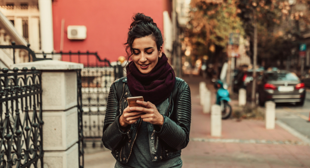 woman walking on city street on cell phone