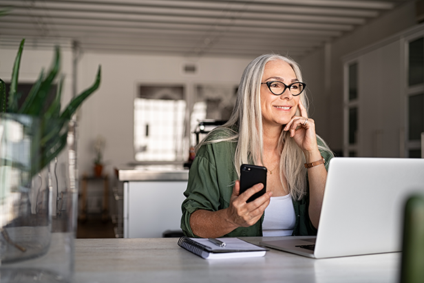 Smiling senior woman managing online payments at home.