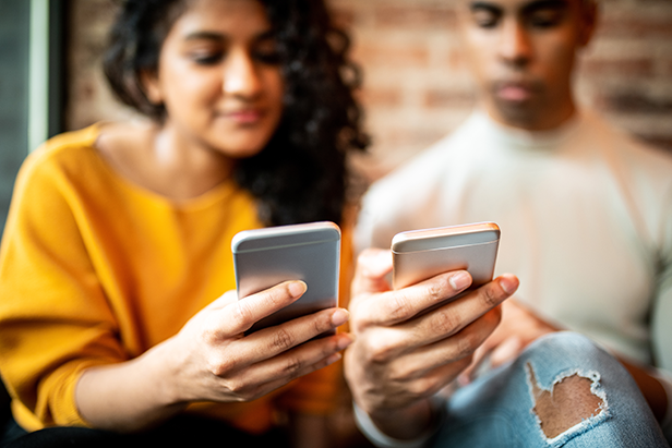 Diverse young adults making a peer-to-peer payment via smartphones.